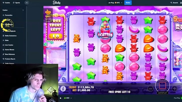 Un homme regarde concentré son écran qui diffuse une partie du jeu d'argent Sugar Rush sur un site de casino en ligne. 