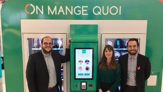 Les trois personnes à côté d'un distributeur d'aliments