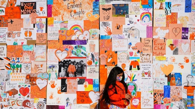 A child stands by a wall of "Every Child Matters" artwork during the National Day for Truth and Reconciliation in Ottawa on Sept. 30, 2021. (Sean Kilpatrick/Canadian Press.)