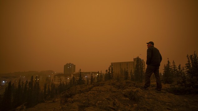 A person in Yellowknife looks at a smoky sky.