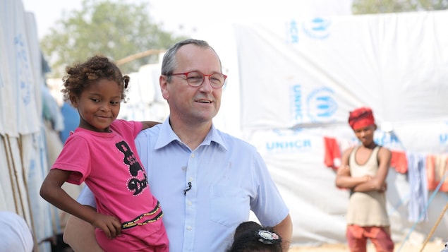 Un homme tient une fillette souriante dans ses bras.