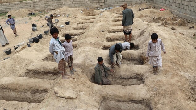 Des enfants sur des tombes préparées pour les victimes de l'attaque aérienne de jeudi dans la province de Saada, au Yémen.