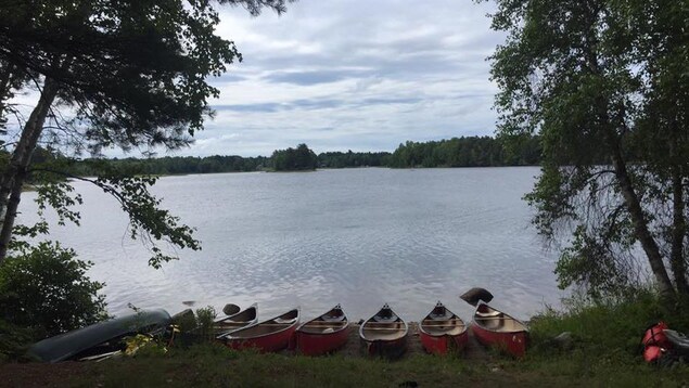 Des canots reposent sur le bord d'un lac. Des canots reposent sur le bord d'un lac.