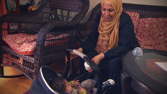 Une femme voilée regarde son petit garçon assis dans un siège d'auto pour enfant. Une femme voilée regarde son petit garçon assis dans un siège d'auto pour enfant.