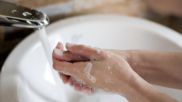 Une femme se lave les mains avec du savon.