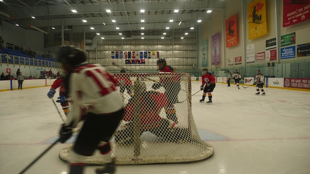 Des joueuses de hockey se dispute la rondelle sur la glace autour d'un but.