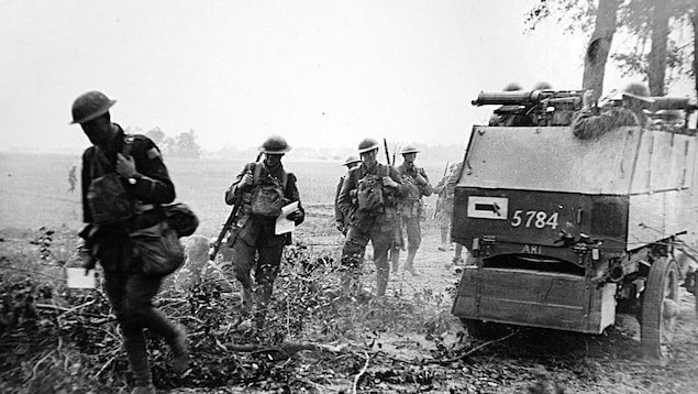 Photo noir et blanc de soldats marchant dans un champ, à côté d'un char d'assaut. Photo noir et blanc de soldats marchant dans un champ, à côté d'un char d'assaut.