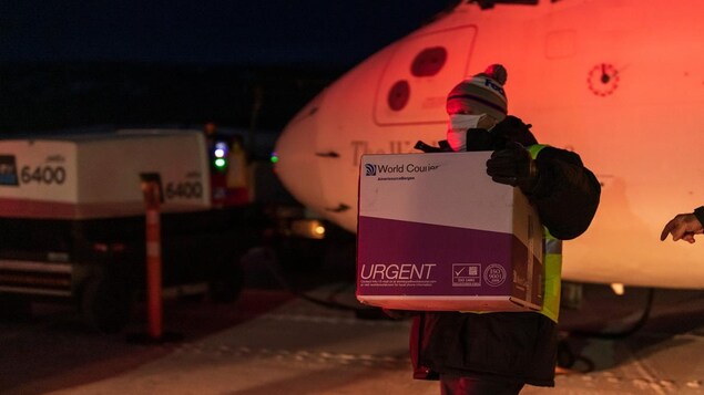 Une boîte en carton est transportée près d'un avion.