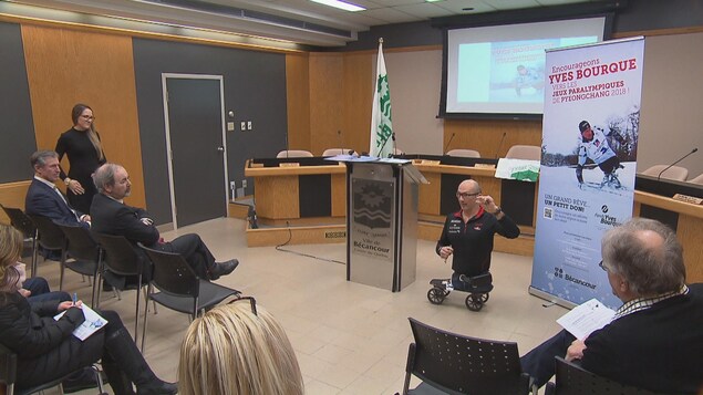 Un homme dépourvu de jambes et installé sur une planche roulante donne une conférence de presse dans la salle du conseil municipal de Bécancour. Un homme dépourvu de jambes et installé sur une planche roulante donne une conférence de presse dans la salle du conseil municipal de Bécancour.