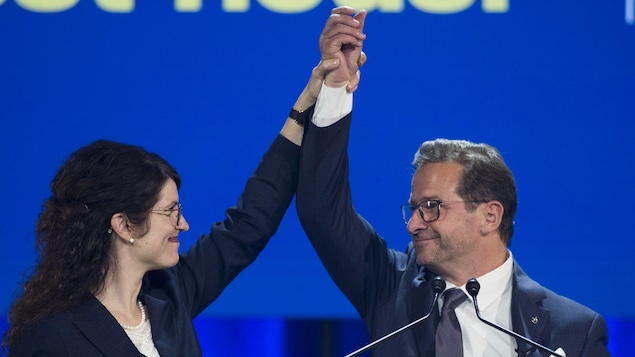 Yves-François Blanchet tient haut des les airs la main de sa conjointe.