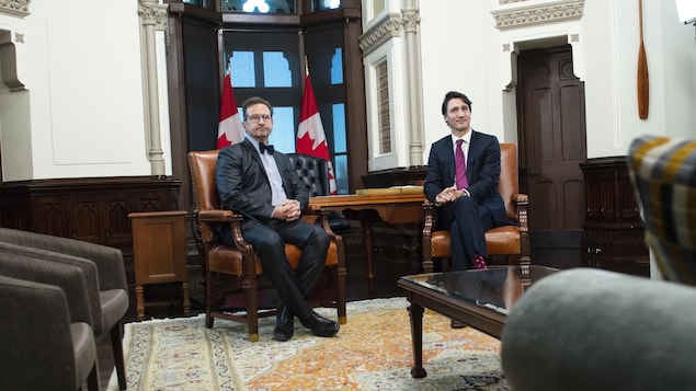 MM. Blanchet et Trudeau assis côte à côte dans une salle remplie de fauteuils.