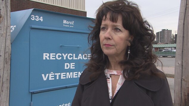 Une femme devant un bac de dons Une femme devant un bac de dons
