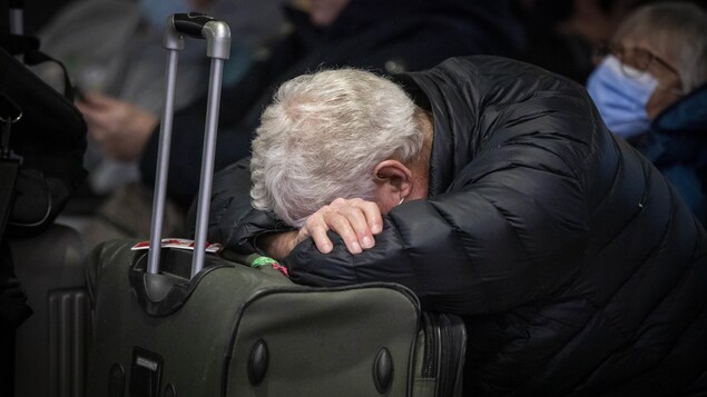 ينام أحد الركاب على حقيبته في مطار فانكوفر بعد إلغاء الرحلات في 20 ديسمبر 2022.