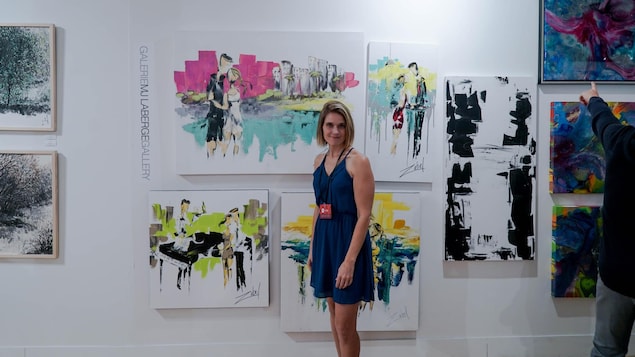 Isabelle Parent devant des toiles et le logo de MJ Laberge Gallery.