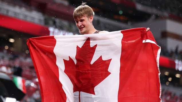 Zachary Gingras est heureux en tenant un drapeau canadien.