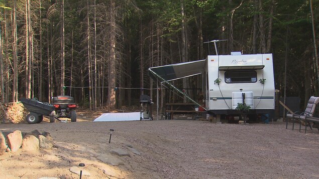 Une roulotte avec une table de pique-nique, un barbecue et des chaises d'extérieur