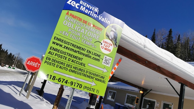 Une affiche devant un bâtiment d'accueil en hiver.