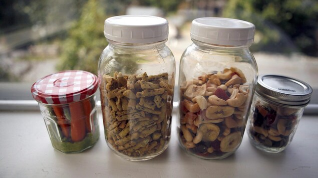 4 bocaux en verre remplis d'aliments : noix, biscuits, carottes