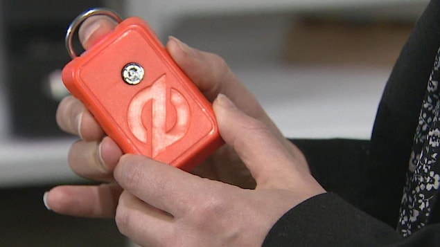 Une personne tient entre ses mains un petit appareil de couleur orange.
