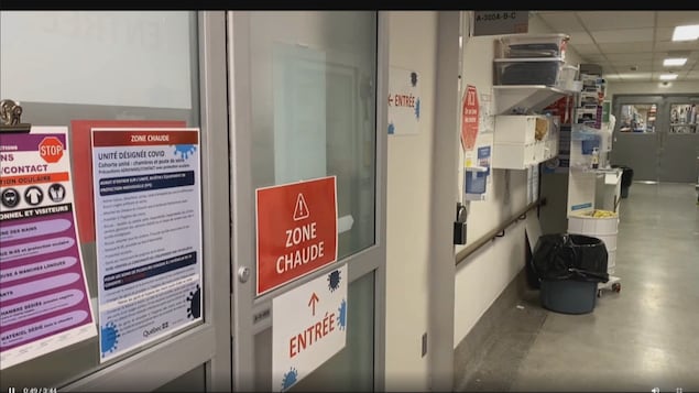 Une porte sur laquelle est écrit zone chaude et entrée dans un corridor de l'hôpital de Chicoutimi.
