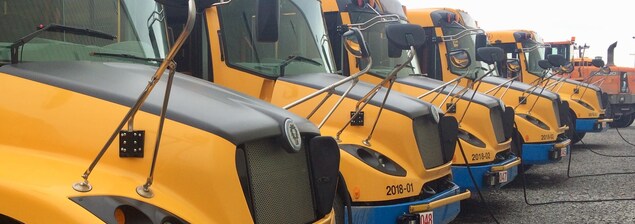 Une série d'autobus scolaires électriques branchés aux bornes de recharge. Une série d'autobus scolaires électriques branchés aux bornes de recharge.