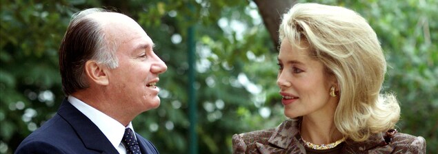 Le prince parle à sa femme, qui l'écoute en souriant. Le couple est entouré d'arbres. Le prince parle à sa femme, qui l'écoute en souriant. Le couple est entouré d'arbres.