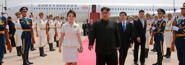 Kim Jong-un et sa femme Ri Sol-ju marchent sur un tapis rouge en sortant d'un avion. Kim Jong-un et sa femme Ri Sol-ju marchent sur un tapis rouge en sortant d'un avion.
