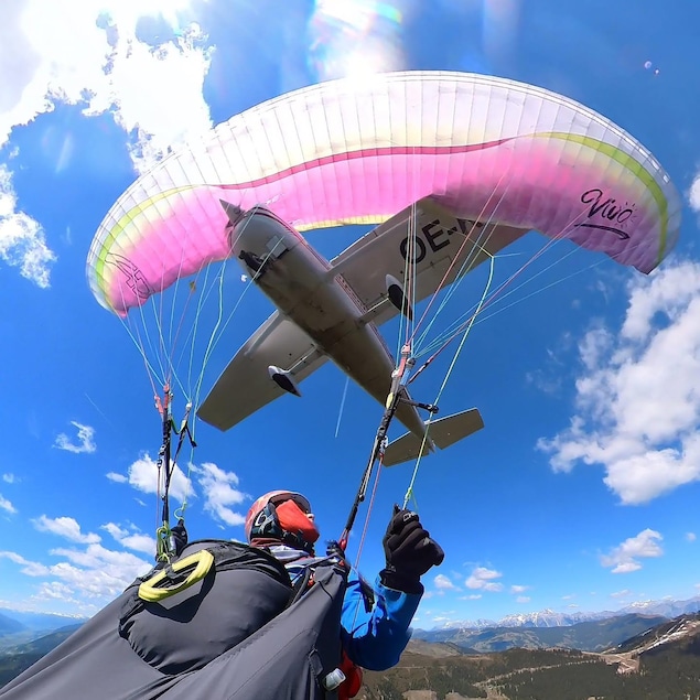 Une parapentiste regarde derrière elle et constate qu'un avion est en train de foncer dans la voile de son parapente.