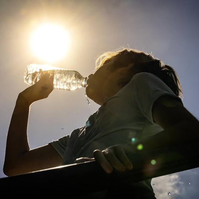 Une personne boit de l'eau lors dune journée ensoleillée.