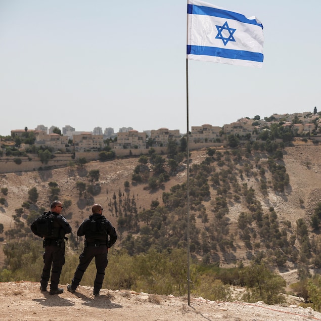 Un drapeau israélien flotte, alors qu'une partie de la colonie israélienne de Maale Adumim est visible à l'arrière-plan, en Cisjordanie occupée par Israël, le 14 août 2025.