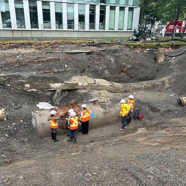 Des élus et des fonctionnaires de la Ville de Montréal près d'une conduite d'eau brisée.