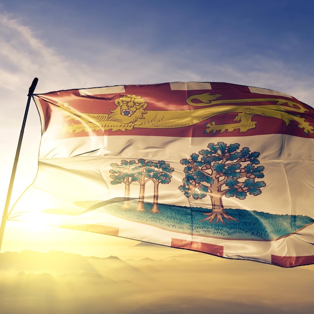 Le drapeau de l'Île-du-Prince-Édouard flotte devant un lever de soleil.