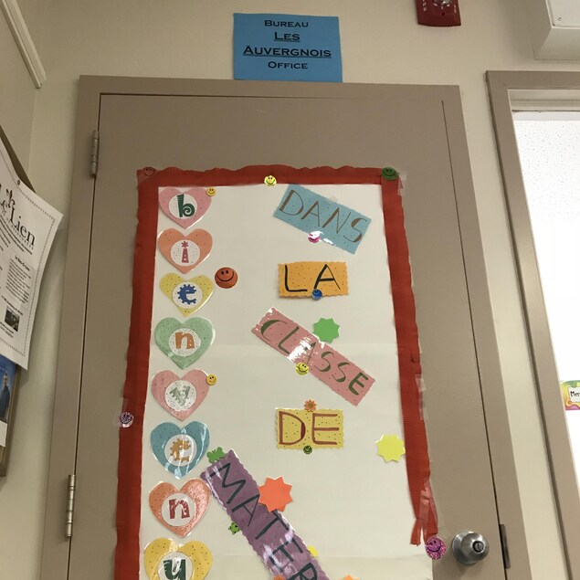 Au-dessus d'une porte beige se trouve une affiche indiquant le bureau des Auvergnois de Ponteix. Sur une grande affiche qui couvre presque complètement la porte, on peut lire: « Bienvenue dans la classe de maternelle ». Au-dessus d'une porte beige se trouve une affiche indiquant le bureau des Auvergnois de Ponteix. Sur une grande affiche qui couvre presque complètement la porte, on peut lire: « Bienvenue dans la classe de maternelle ».