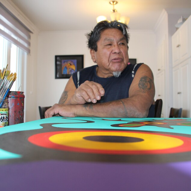 Frank Polson est assis devant une toile.