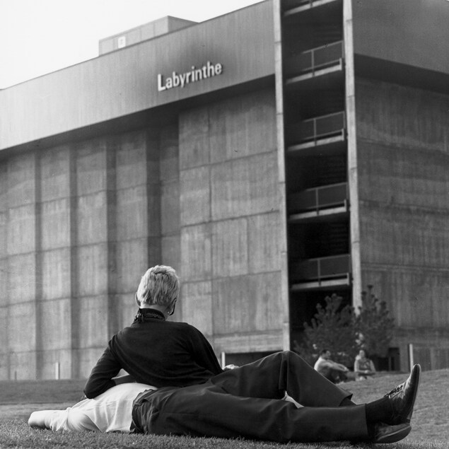 Un couple se repose dans l'herbe, devant le pavillon du Labyrinthe, à l'Expo 67. Un couple se repose dans l'herbe, devant le pavillon du Labyrinthe, à l'Expo 67.