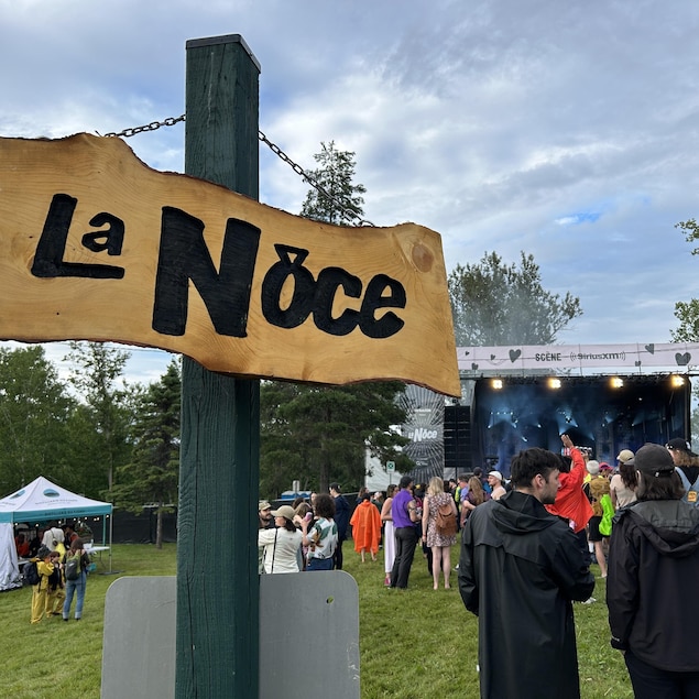 Une affiche de festival est placée derrière une foule.