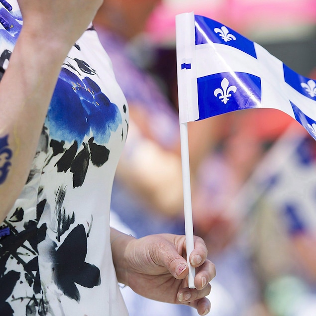 Une femme tient le drapeau québécois lors des célébrations de la fête nationale.