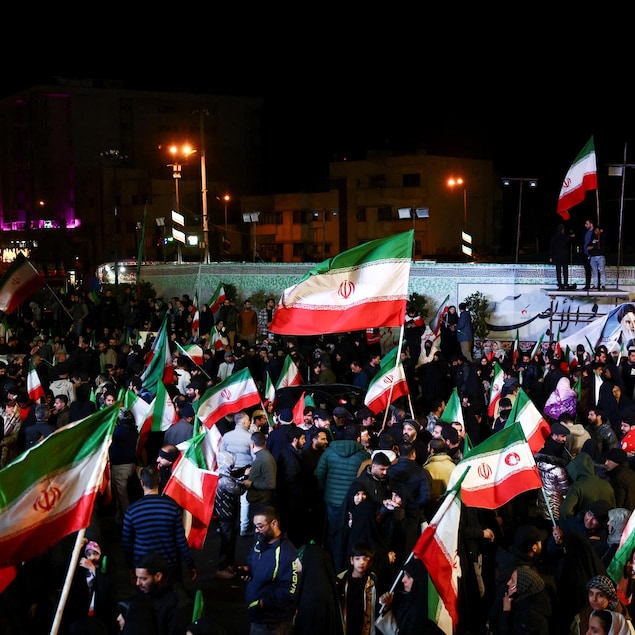 Des drapeaux iraniens flottent au-dessus d'une foule.