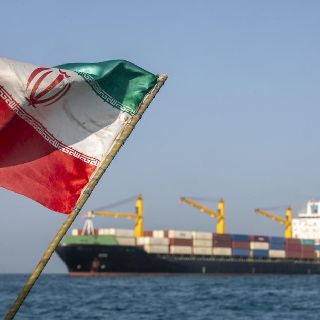 Un drapeau de l'Iran flotte devant un bateau sur l'eau.