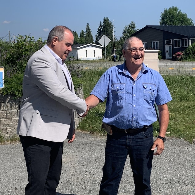 Martin Ferron et Yvon Charette, tout sourire, se serrent la main.