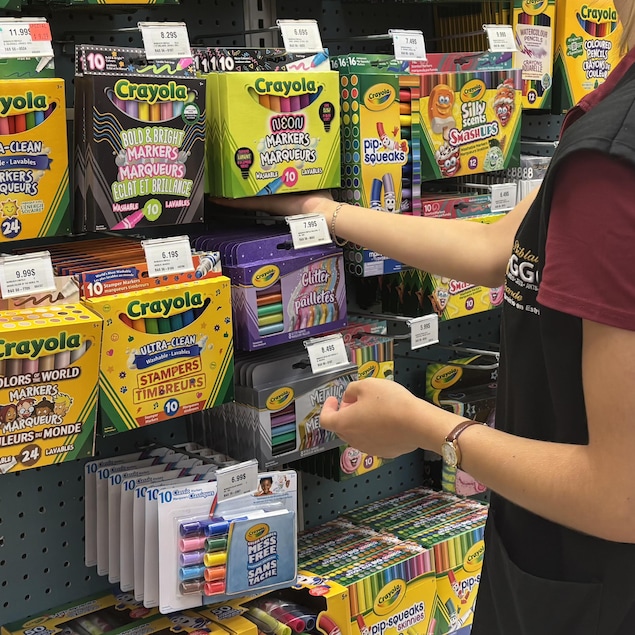 Une employée de la Biblairie GGC range des crayons dans un étalage. 