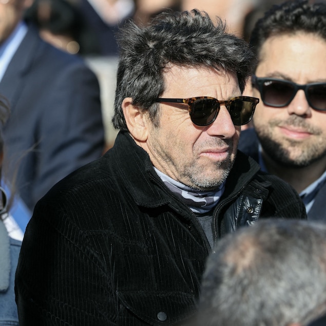 Un homme portant des lunettes de soleil est debout dans une foule.