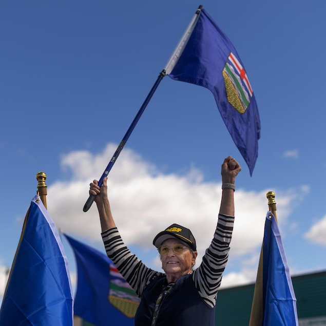 Une personne agite un drapeau de l'Alberta.