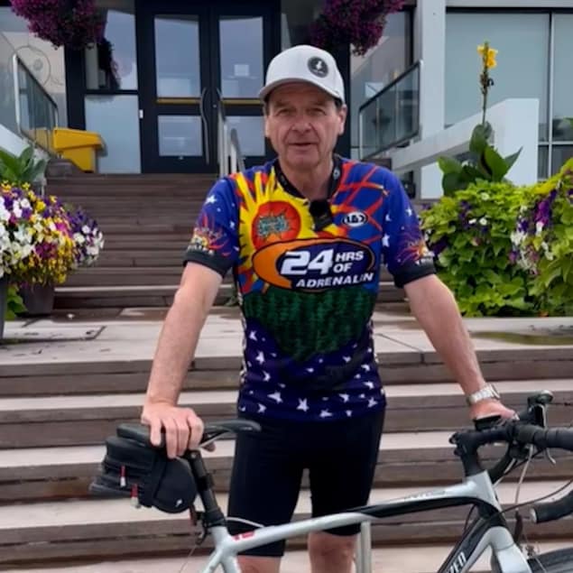 Serge Allard debout devant son vélo.