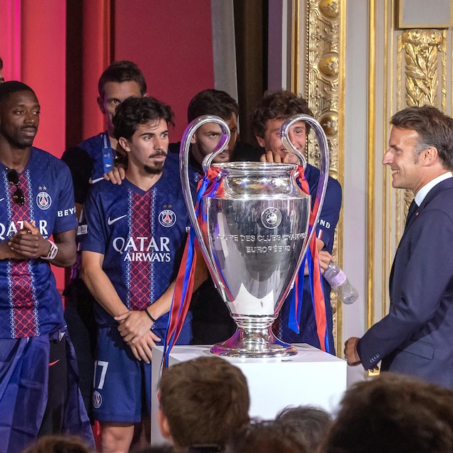 Le président français, Emmanuel Macron, arrive devant les joueurs et leur trophée.