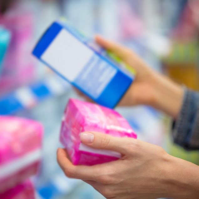 Une personne choisissant ses produits menstruels au magasin.