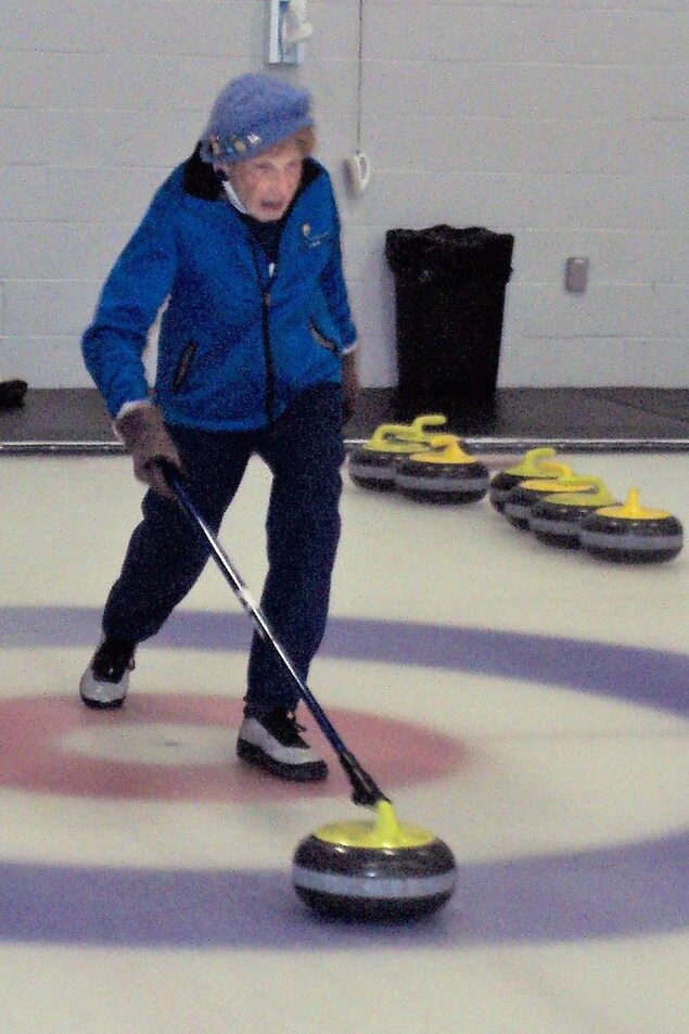 Une femme âgée qui joue au curling Une femme âgée qui joue au curling