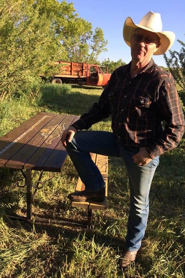 Un homme vêtu d'une chemise à carreaux et d'un chapeau de cowboy pose le pied sur une table à pique-nique. Un homme vêtu d'une chemise à carreaux et d'un chapeau de cowboy pose le pied sur une table à pique-nique.