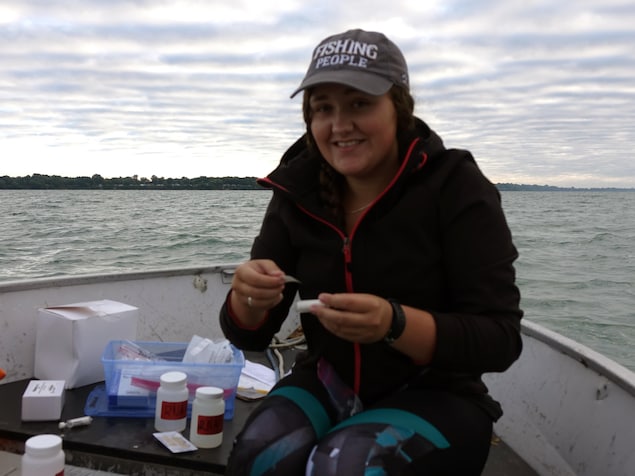 On voit Mme Gauvin qui sourit à la caméra. Elle est assise dans son embarcation. En arrière-plan, le lac Érié. On voit Mme Gauvin qui sourit à la caméra. Elle est assise dans son embarcation. En arrière-plan, le lac Érié.