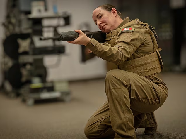 Une soldate en uniforme tient une arme.